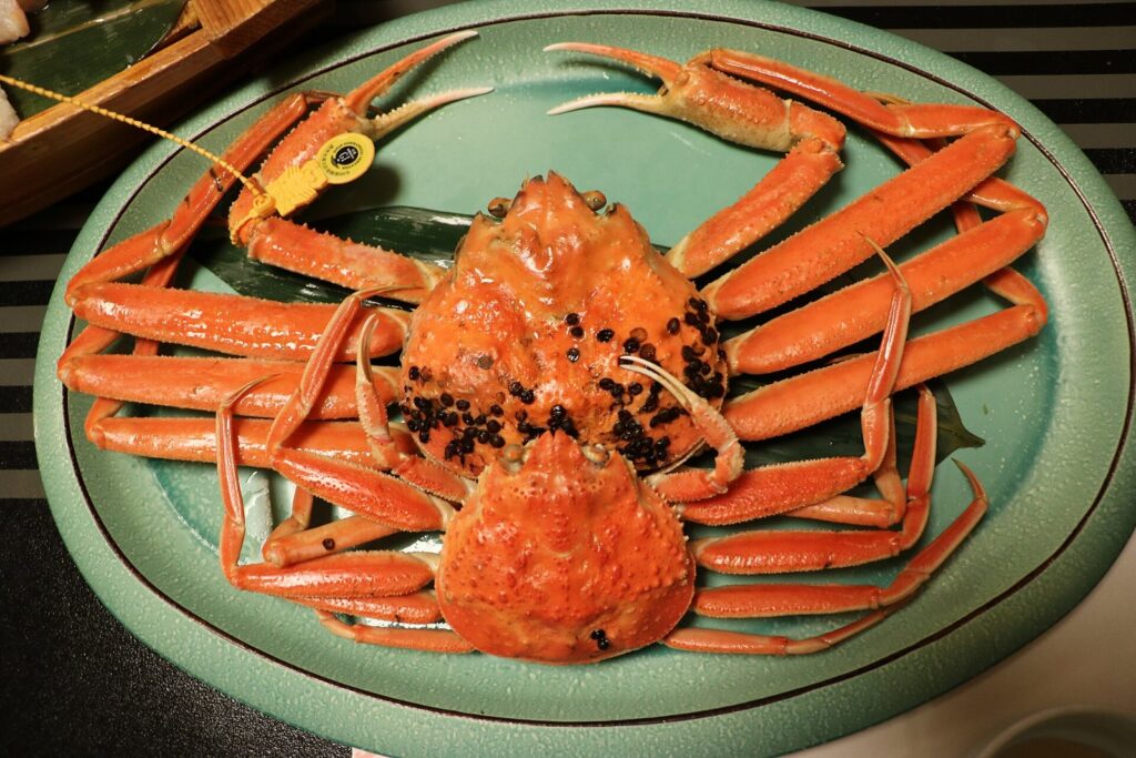 노란 산지 인증 태그가 달린 삶은 에치젠가니 수컷과 알을 품은 암컷이 접시에 놓인 모습.